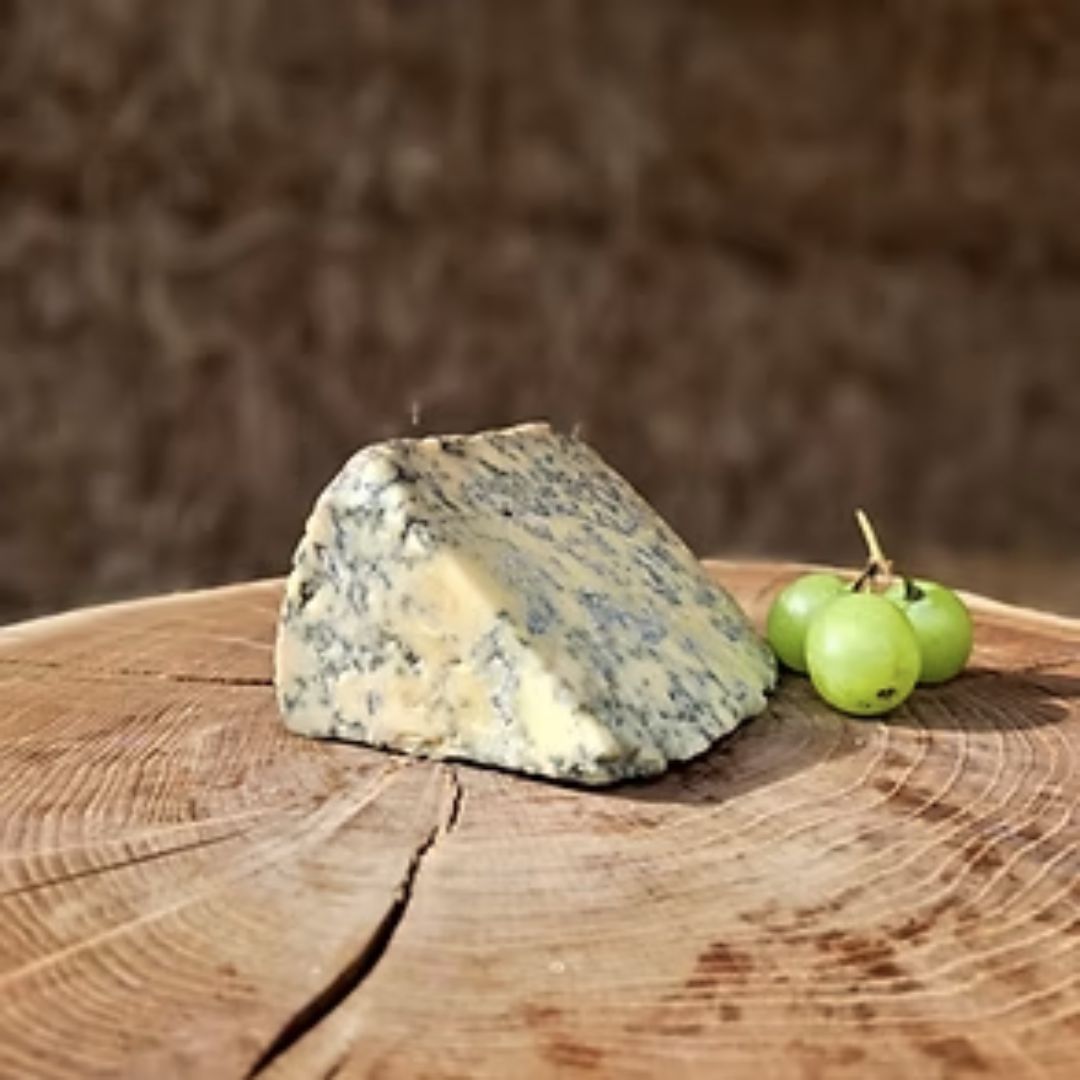 Blue vinny cheese wedge with green grapes on a wooden surface