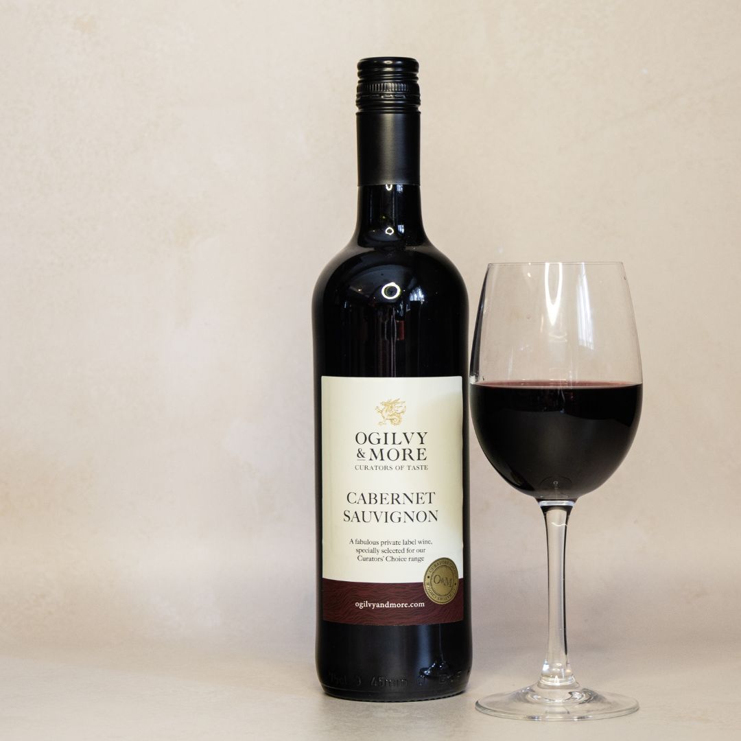 Bottle of Ogilvy & More Cabernet Sauvignon wine with a glass of red wine