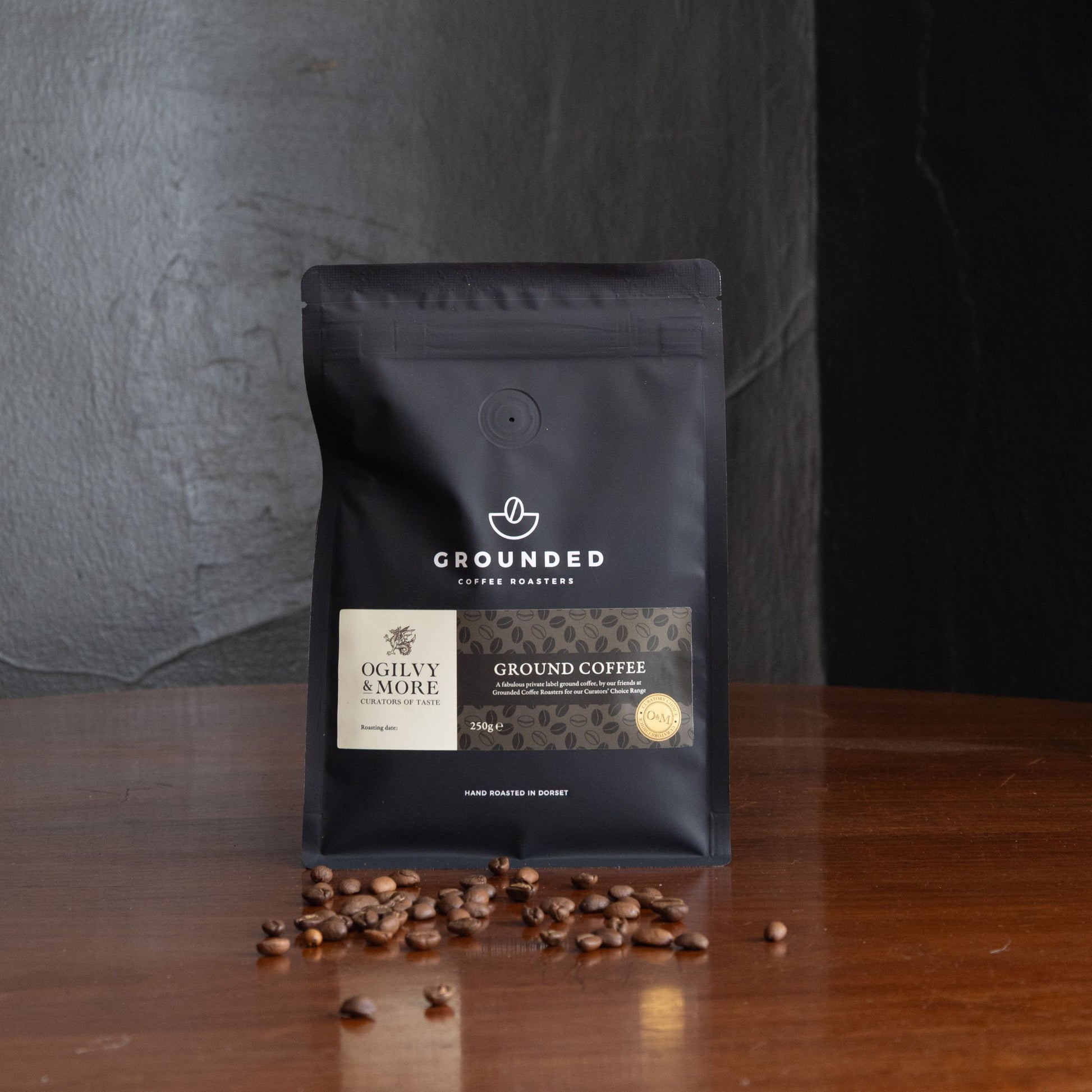 Grounded Coffee Roasters coffee package with scattered coffee beans on a wooden surface.