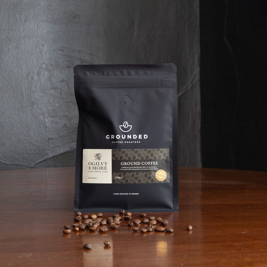 Grounded Coffee Roasters coffee package with scattered coffee beans on a wooden surface.