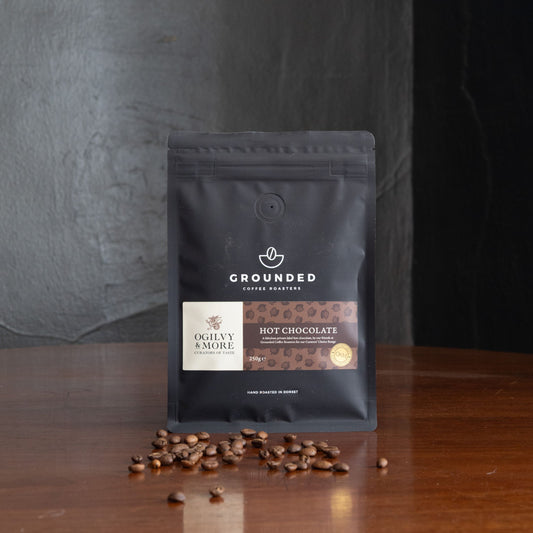 Grounded Hot Chocolate package with coffee beans on a wooden surface