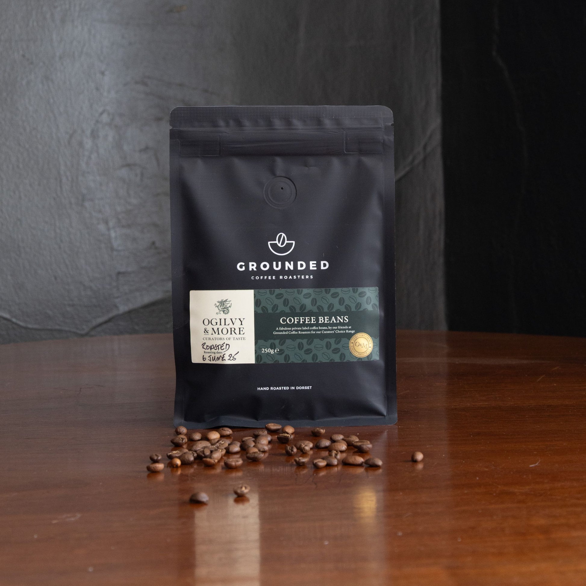 Grounded coffee beans package with scattered coffee beans on a wooden surface