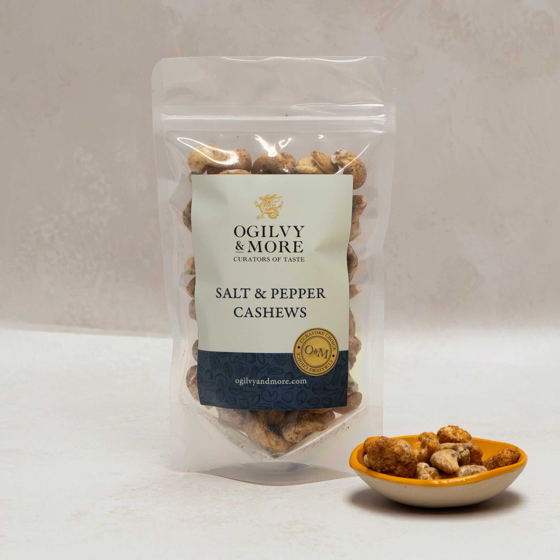 Ogilvy & More salt and pepper cashews with a small bowl of cashews on a light background