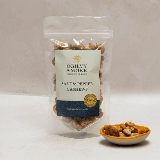 Ogilvy & More salt and pepper cashews with a small bowl of cashews on a light background
