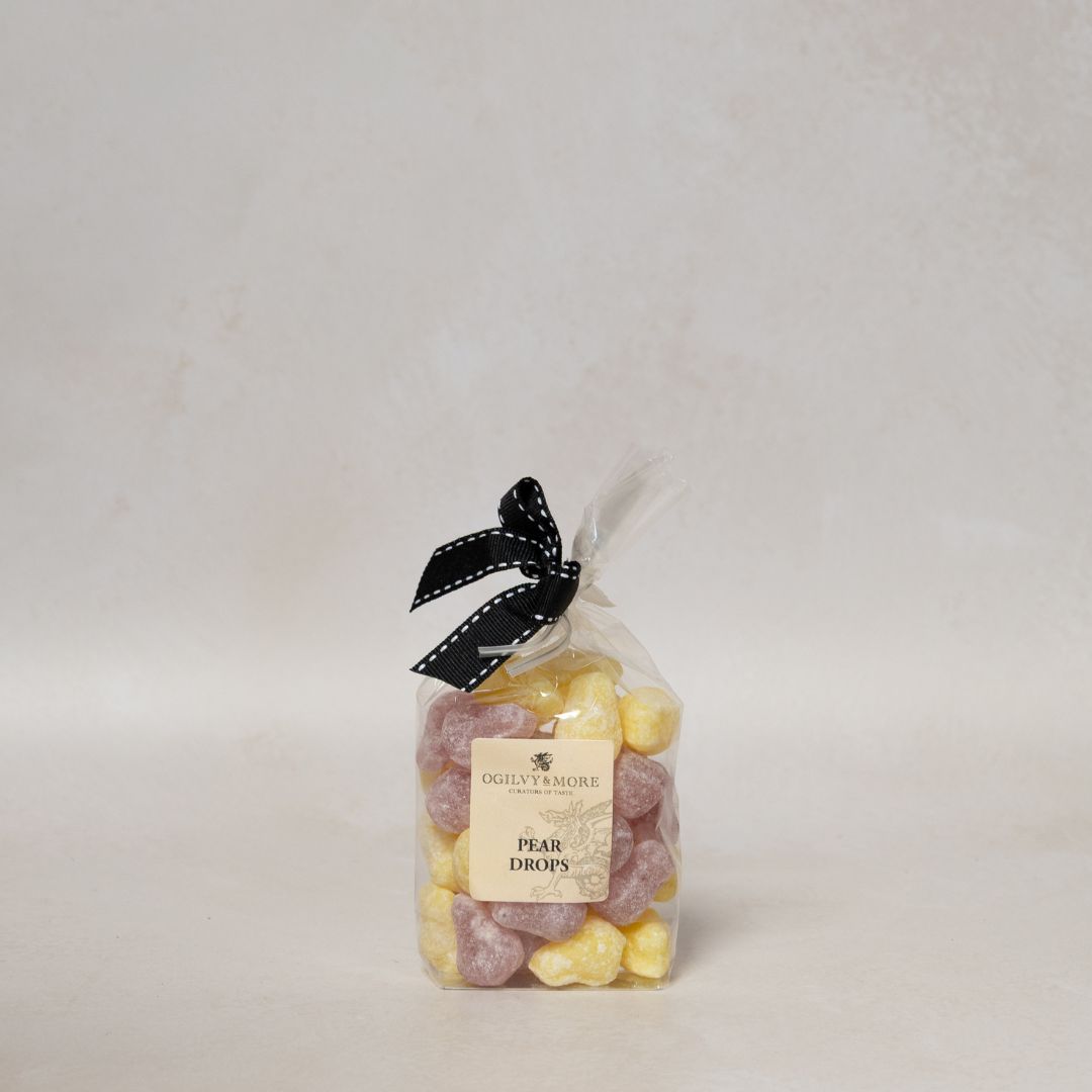 Bag of Ogillvy & More pear drops with a black ribbon on a light gray background
