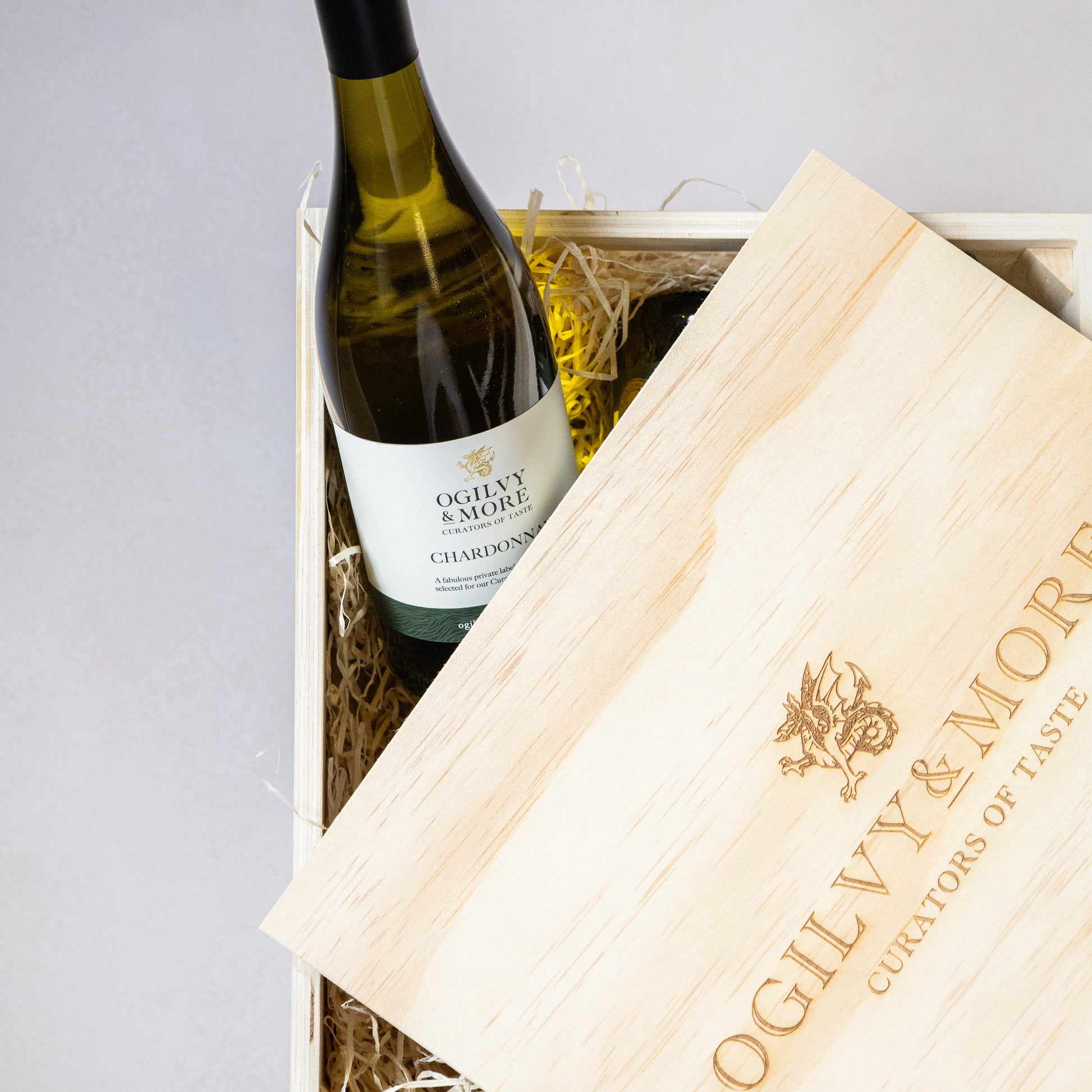 Bottle of Ogilvy & More Chardonnay in a wooden crate with a branded napkin.