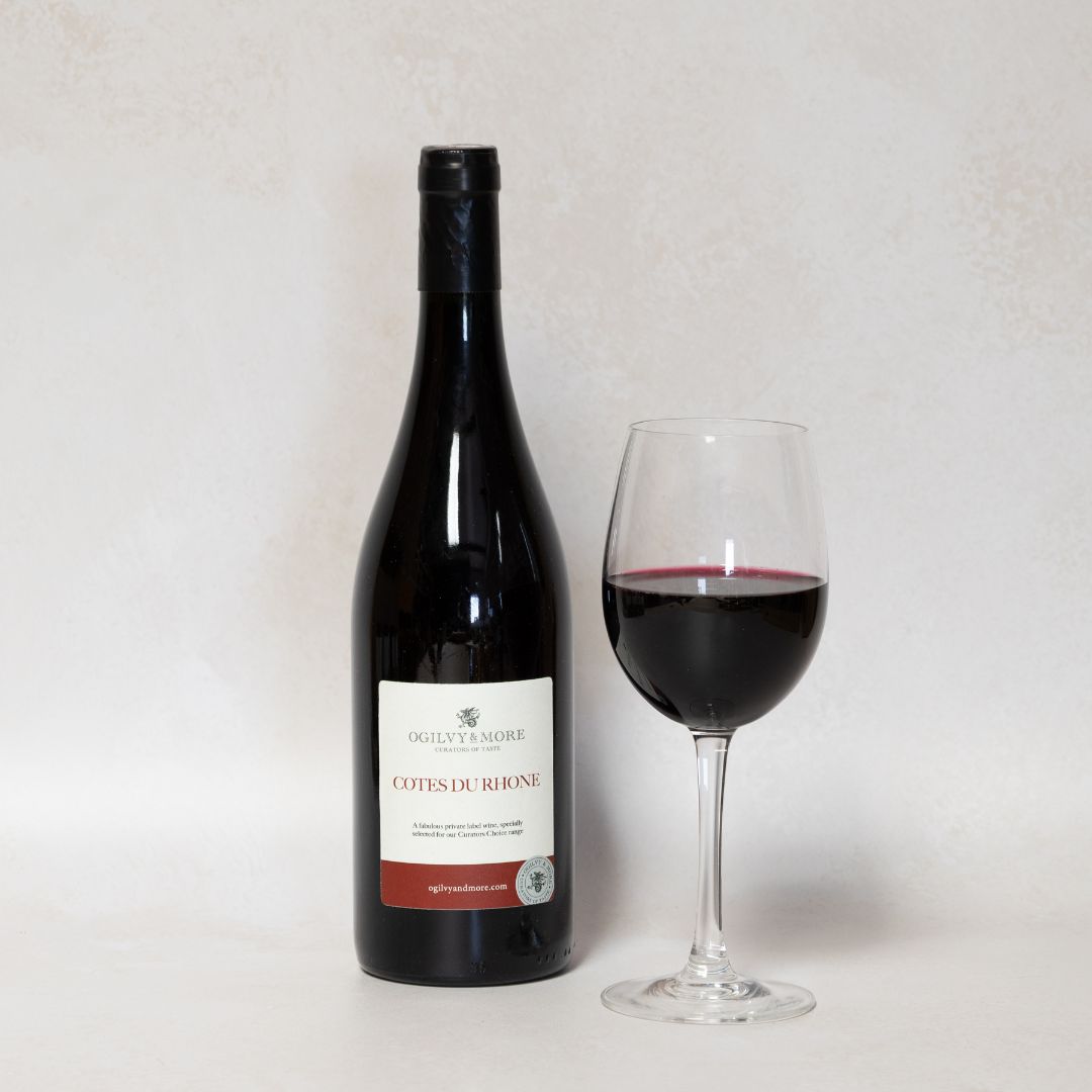 Bottle of Ogilvy & More Cotes du Rhone wine and a glass with a white background