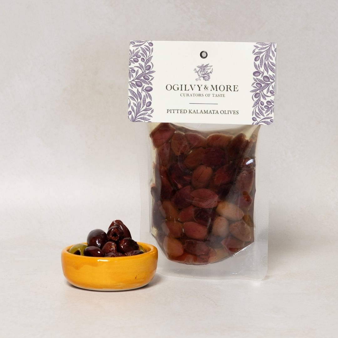 Bag of Ogilvy & More Kalamata olives with a small bowl of olives on a light gray background