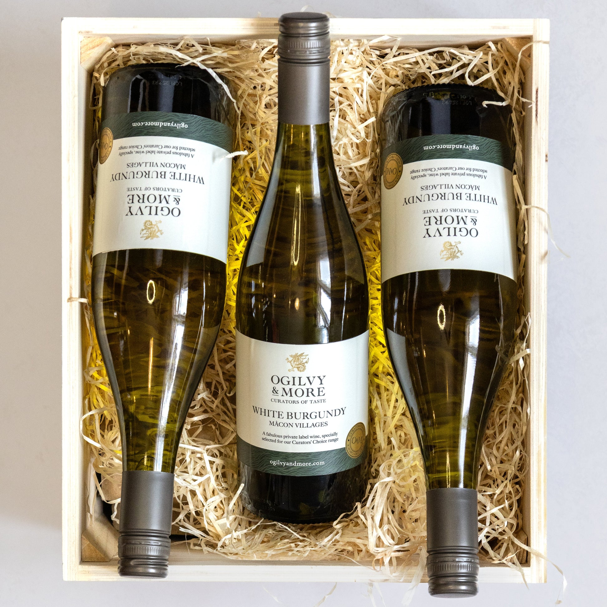 Three bottles of Ogilvy & More Macon villages wine in a wooden box with straw lining.