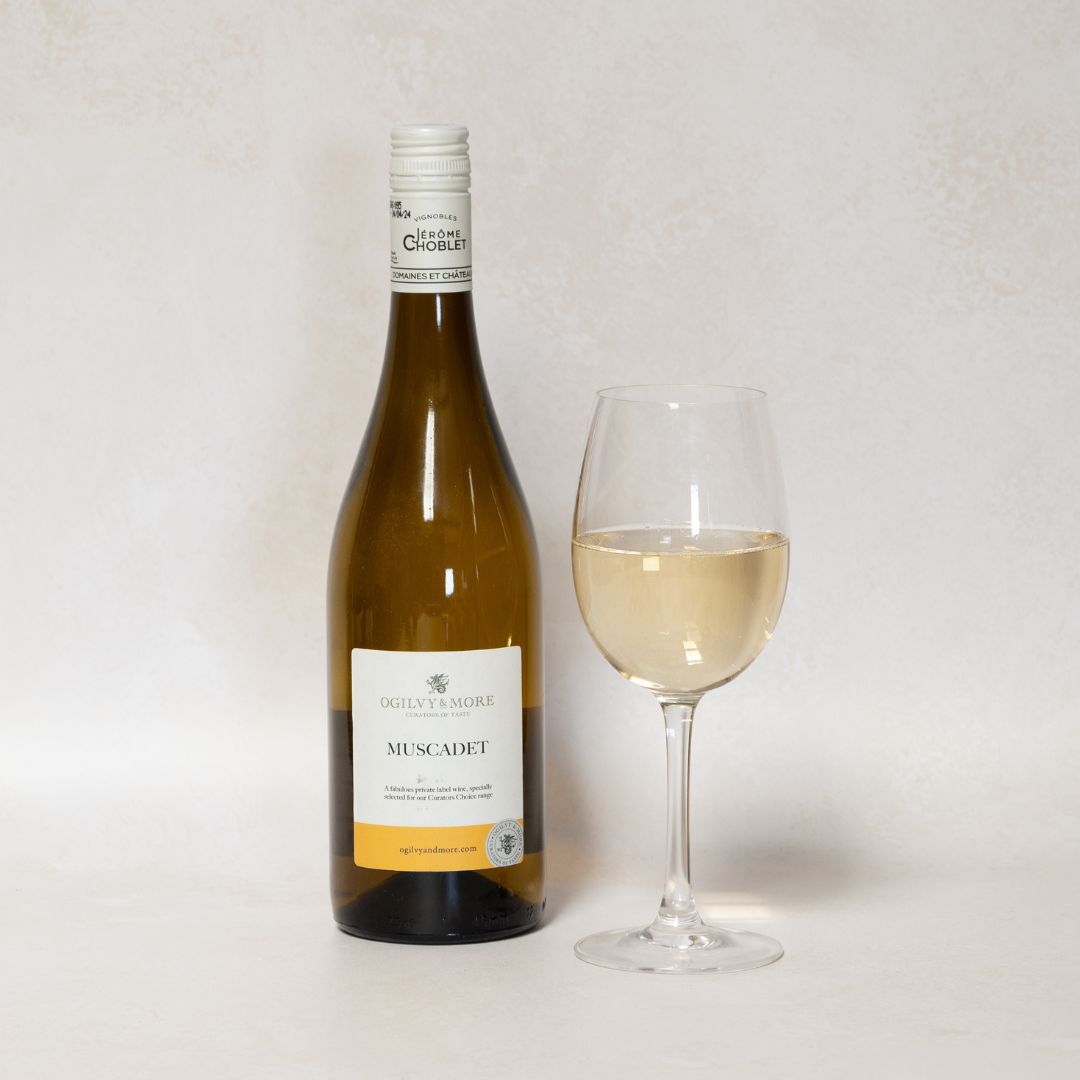 Bottle of Ogilvy & More Muscadet wine with a glass of wine on a light background