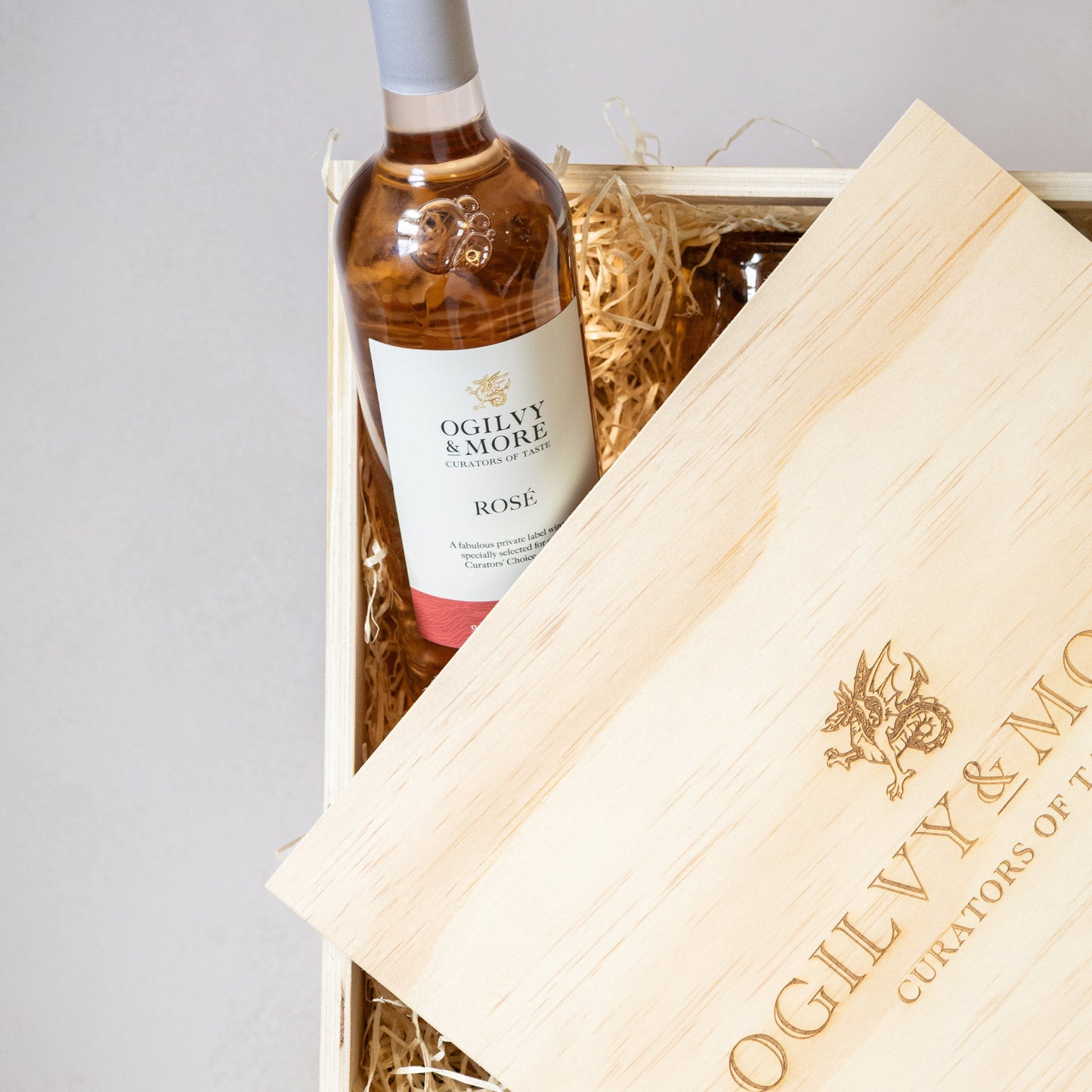 Bottle of Ogilvy & More Rosé wine in a wooden box with branded tissue paper.