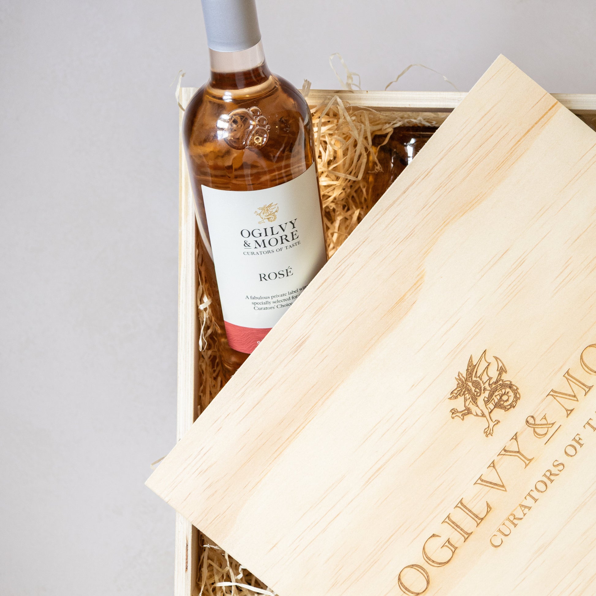 Bottle of Ogilvy & More Rosé wine in a wooden box with branded tissue paper.