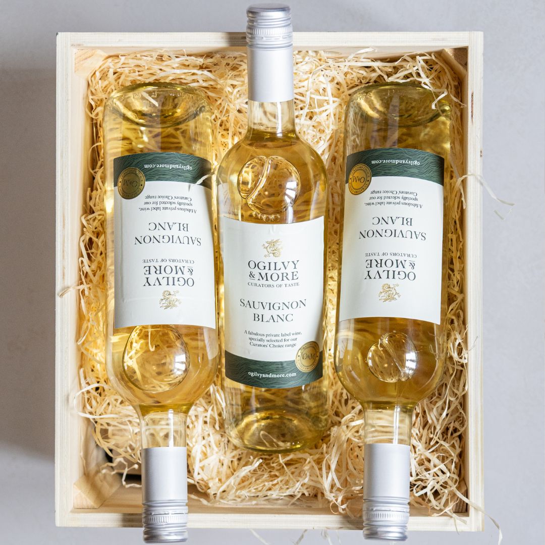 Three bottles of Ogilvy & More Sauvignon Blanc in a wooden crate with straw lining.