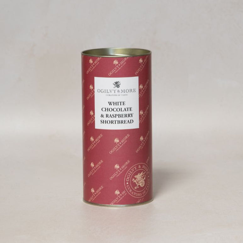 Red cylindrical Ogilvy & More White Chocolate and Raspberry Shortbread tin with white label on a light gray background