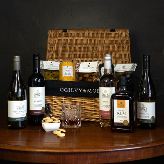 Ogilvy & More Wine bottles and a basket on a wooden table with a dark background