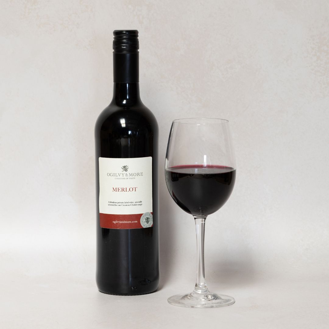 Bottle and glass of Ogilvy & More merlot on a light gray background
