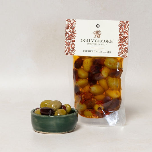 Ogilvy & More paprika chilli olives with a small bowl of olives on a white background
