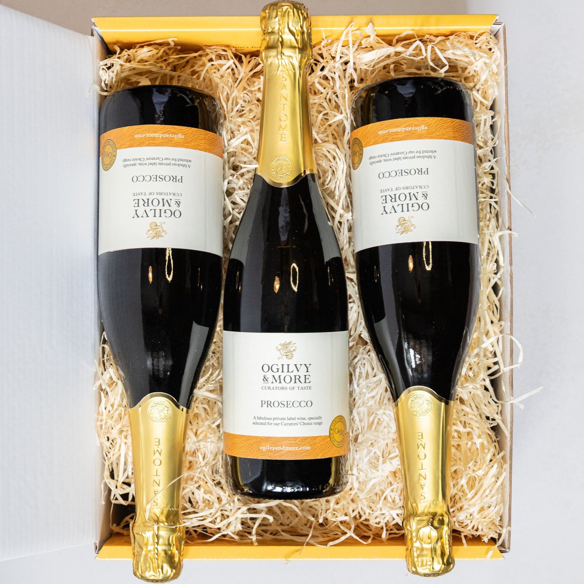 Three bottles of Ogilvy & More prosecco in a decorative box with gold accents.