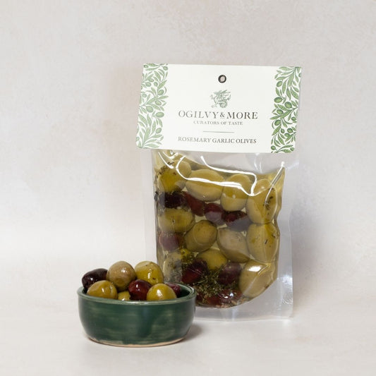 Ogilvy & More rosemary garlic olives with a small bowl of olives on a light gray background