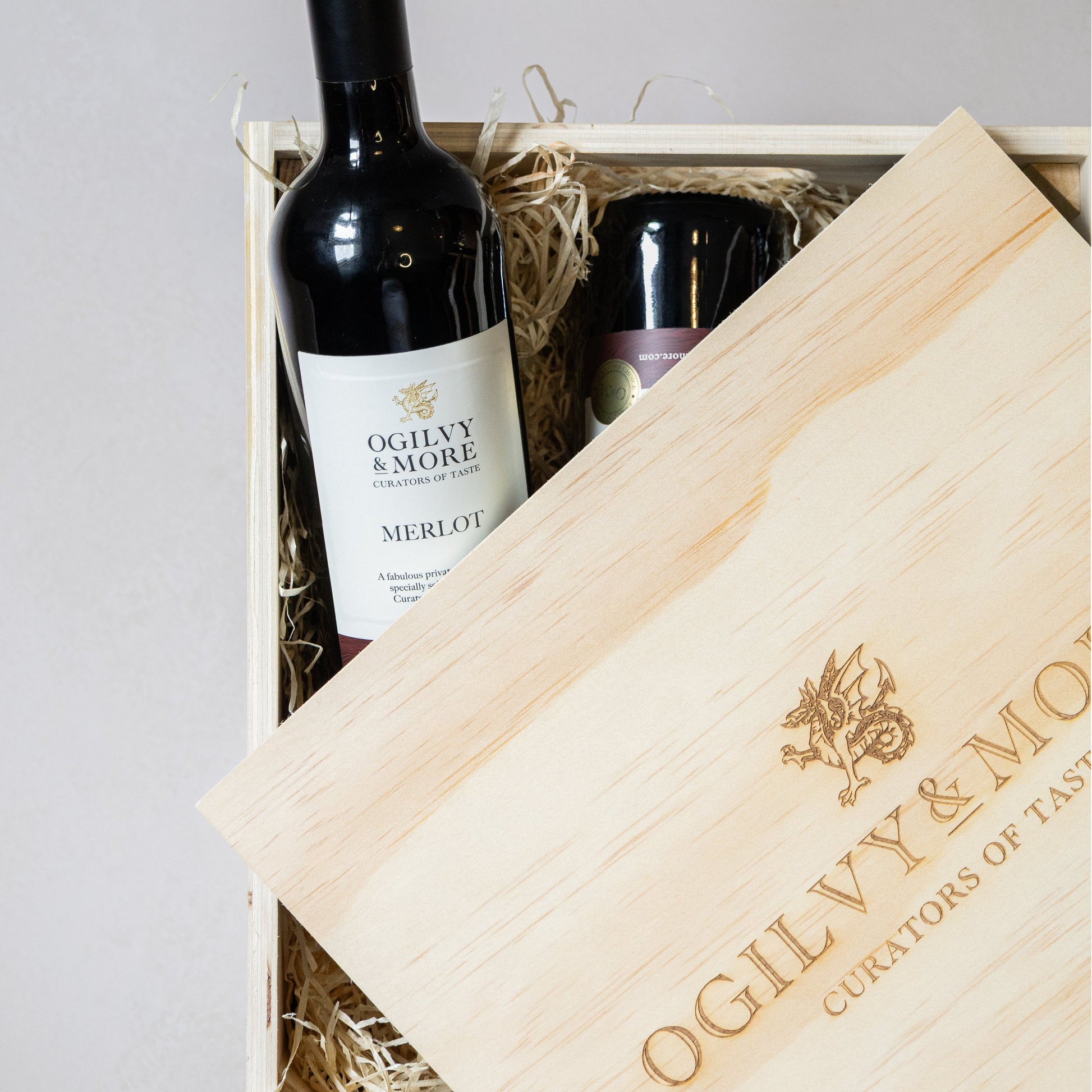 Ogilvy and More Merlot bottles in a wooden crate with branded napkin and box.