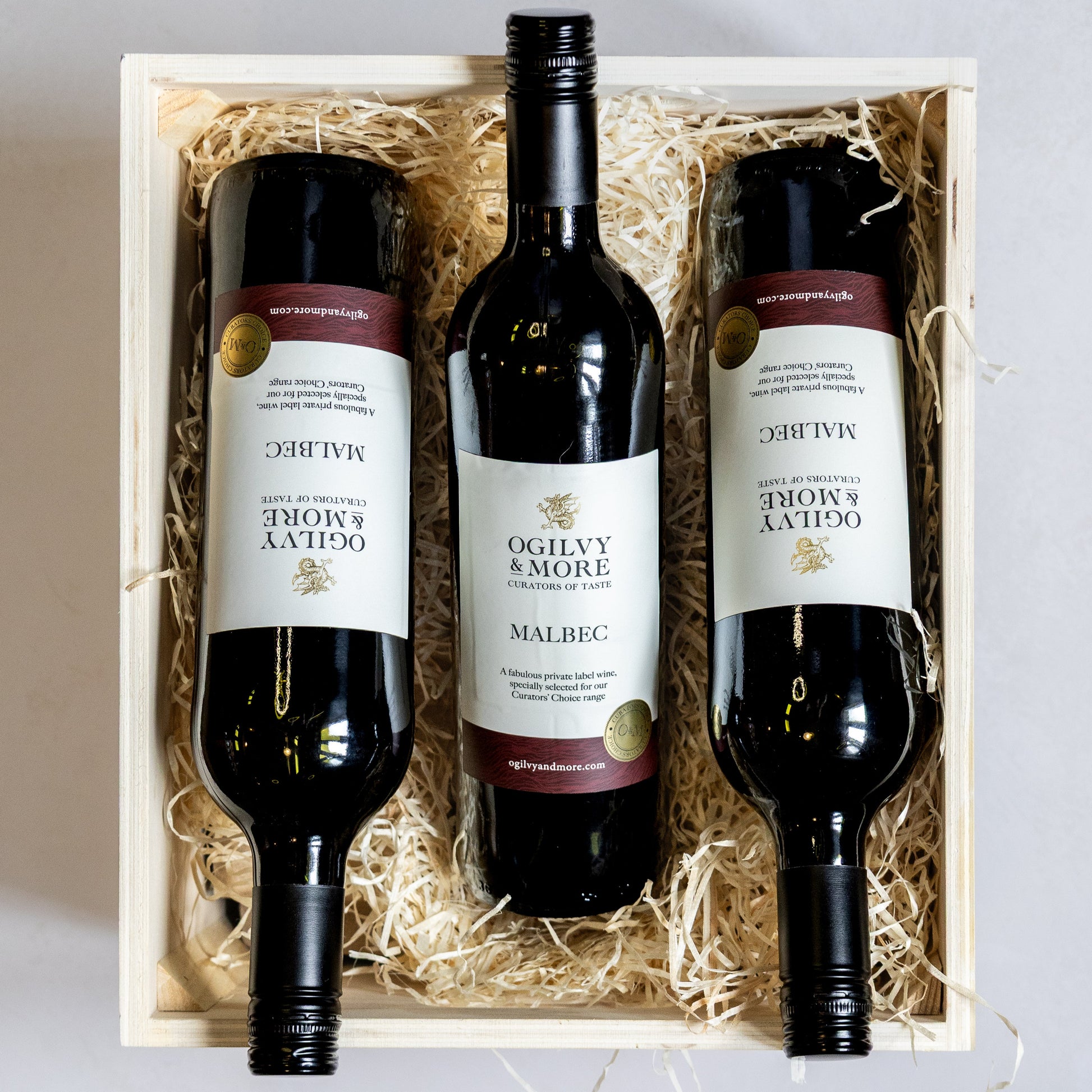 Three bottles of Ogilvy and more malbec wine in a wooden gift box with straw liner.