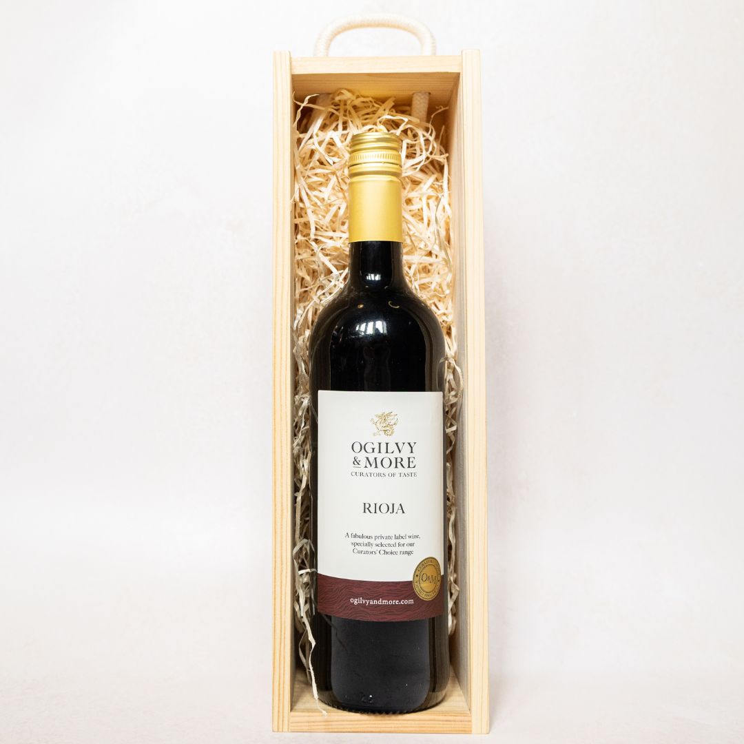 Rioja wine bottle in a wooden box with 'Ogilvy & More' label on a white background