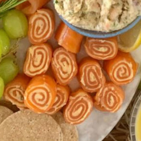 Platter of cold trout assortments, bread, and appetizers with bottles of wine on a table with 'O&M' sign.