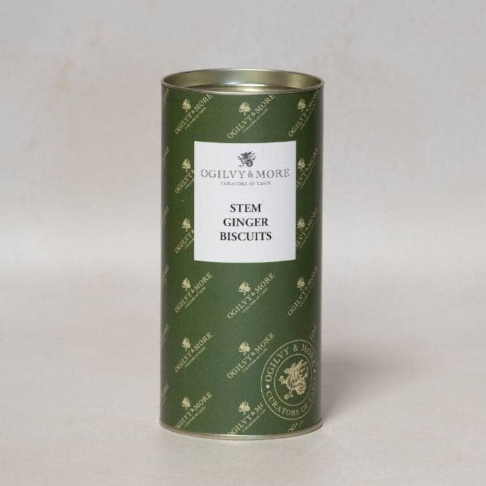 Green cylindrical tin of Ogilvy & More stem ginger biscuits on a light gray background