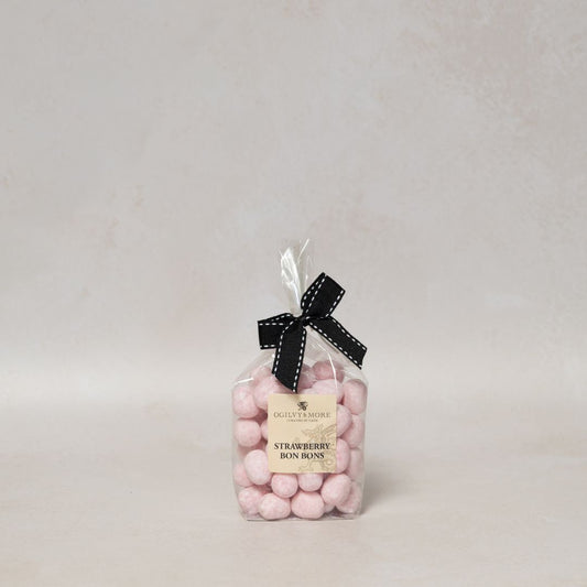 Bag of Ogilvy & More pink strawberry bonbons with a black bow on a light gray background