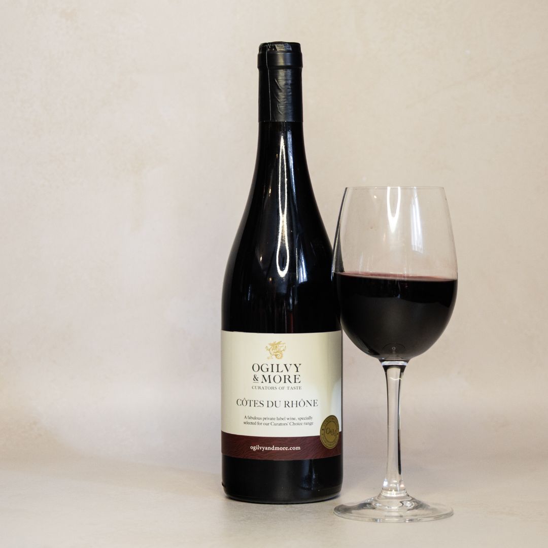 Bottle of Ogilvy & More Cotes du Rhone wine with a glass of red wine