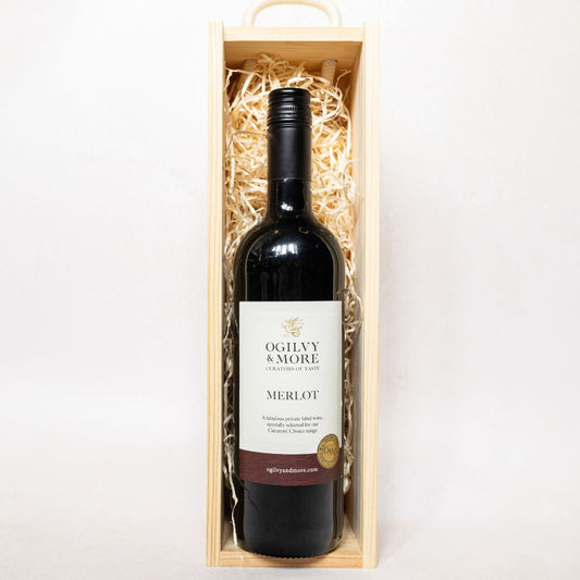 Bottle of Ogilvy & More Merlot wine in a wooden box on a white background