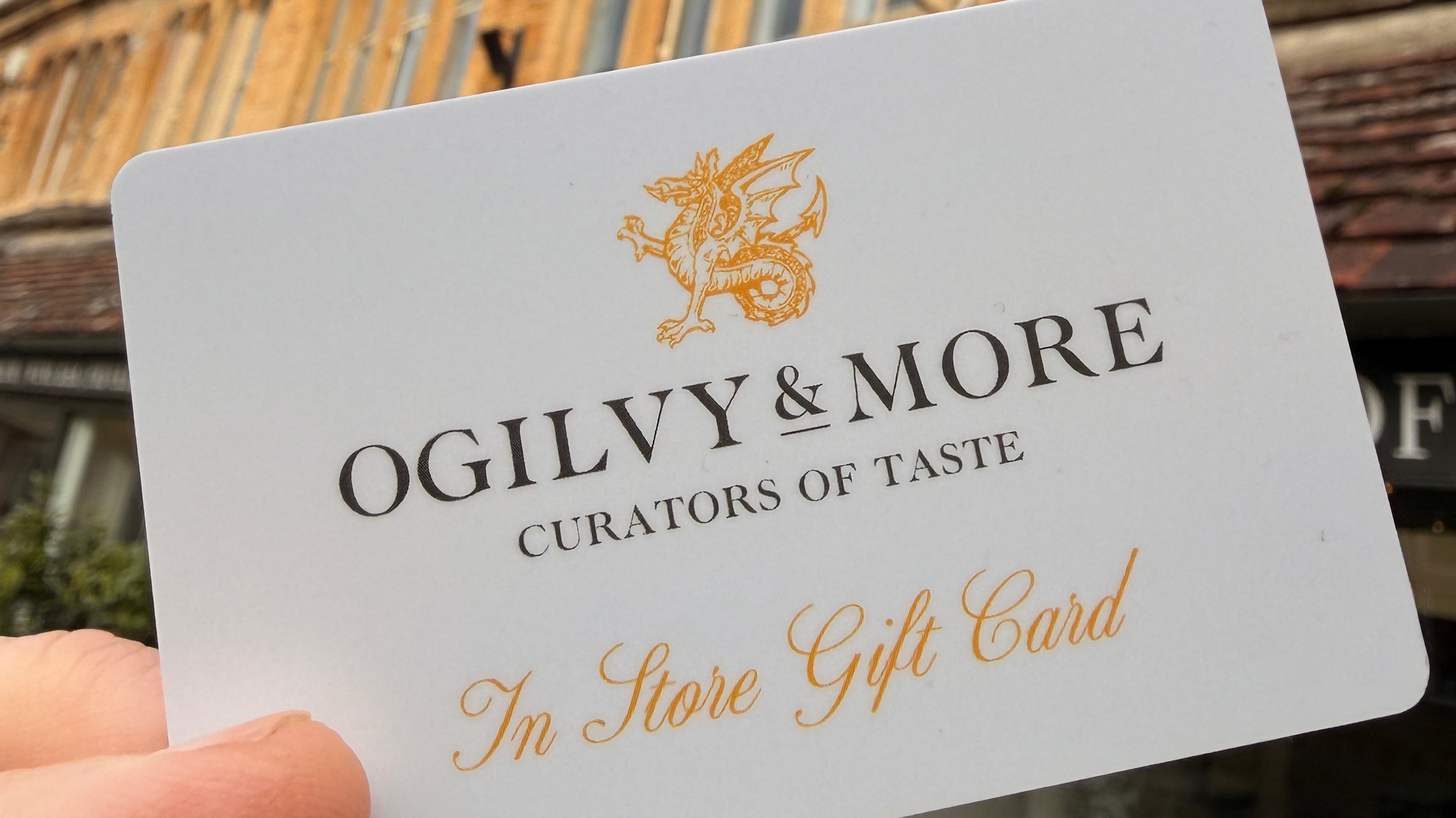 White gift card with gold text held in front of a store entrance