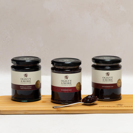Three jars of Ogilvy & More jam on a wooden board with a white background