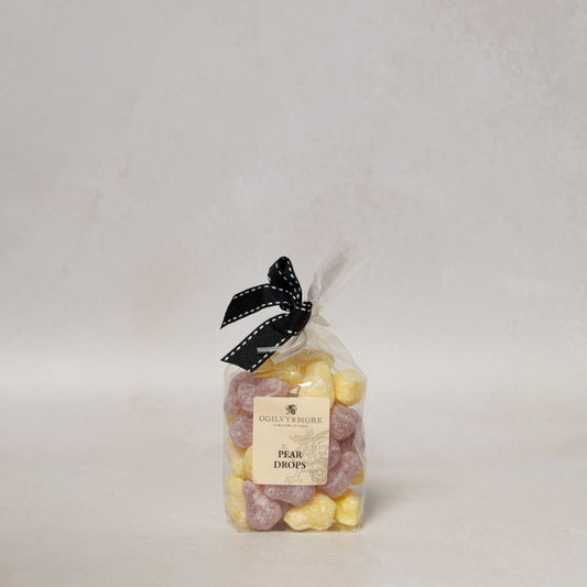Bag of Ogillvy & More pear drops with a black ribbon on a light gray background