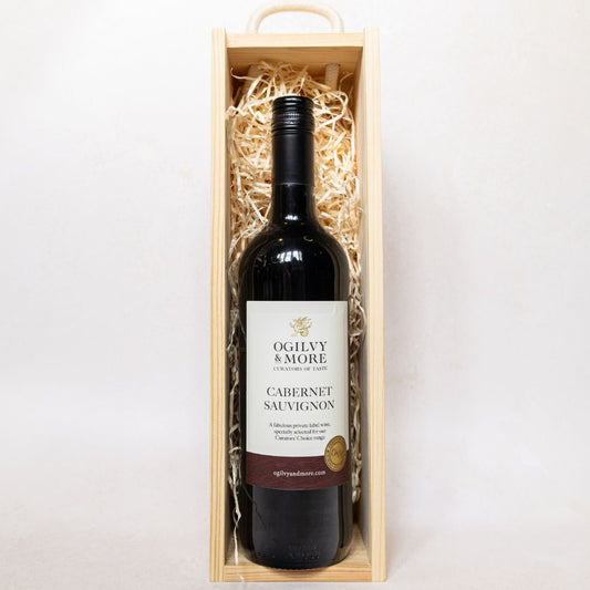 Bottle of Ogilvy & More Cabernet Sauvignon wine in a wooden box on a white background