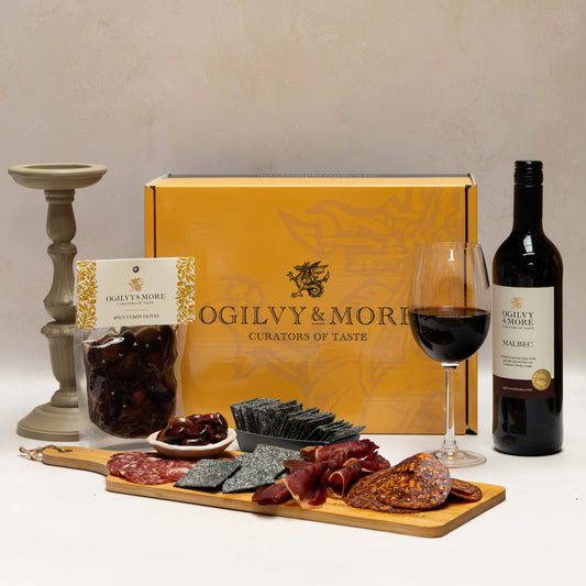 Ogilvy & More Charcuterie and wine gift set with a box, wine bottle, glass, and charcuterie board.