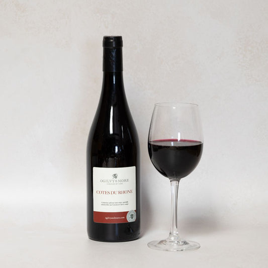 Bottle of Ogilvy & More Cotes du Rhone wine and a glass with a white background