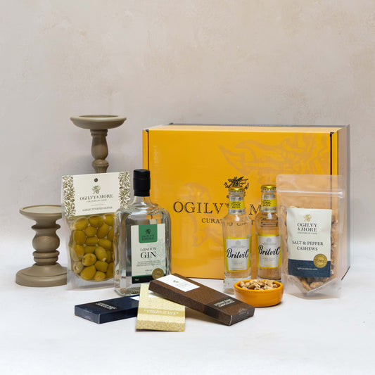 Ogilvy & More Gourmet gift set with bottles, snacks, and a box on a white surface.