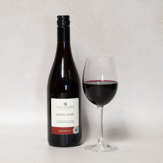Bottle of Ogilvy & More Pinot Noir with a glass of wine on a white background