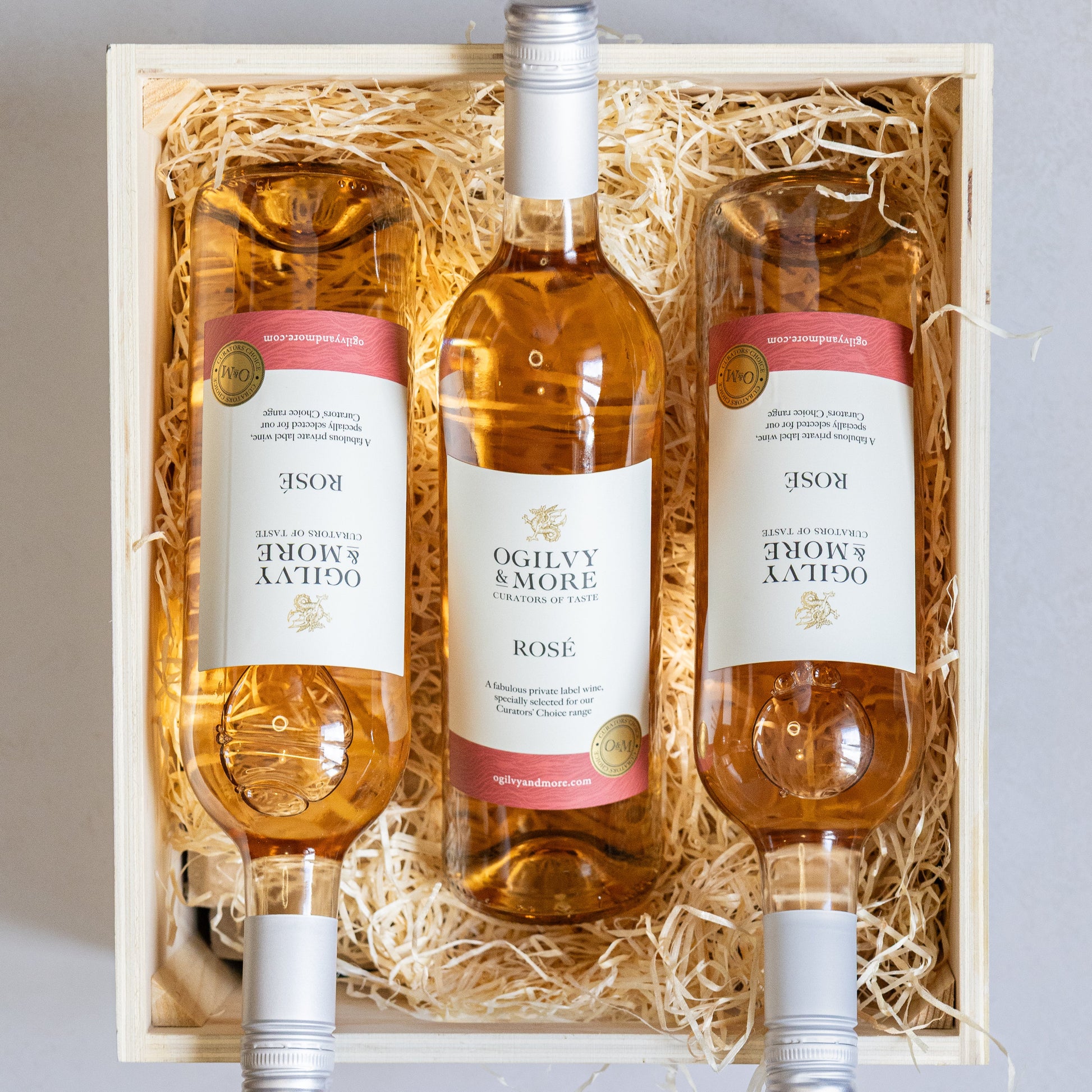 Three bottles of Ogilvy & More Rosé wine in a wooden gift box with straw liner.