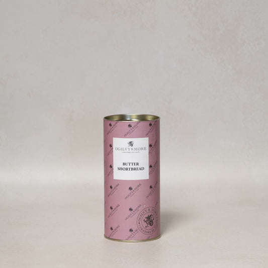Pink cylindrical container of Ogilvy & More butter shortbread with a label on a light gray background