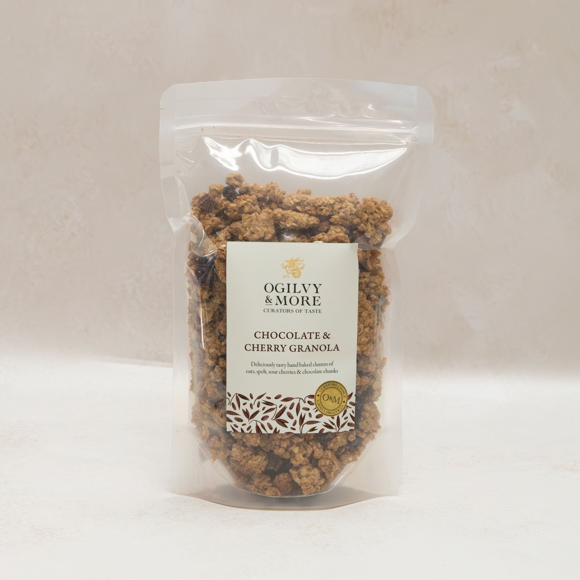 Packaged chocolate and cherry granola with Ogilvy & More label on a light background