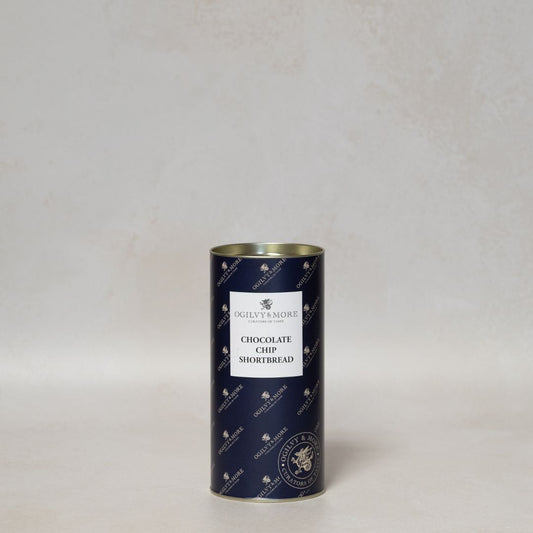 Blue cylindrical tin of Ogilvy & More chocolate chip shortbread with a white label on a light gray background