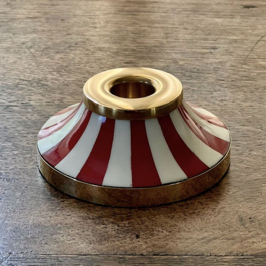 Decorative tooka candle holder with red and white stripes on a wooden surface